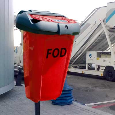 orange FOD 50 bin post mounted at an airport with passenger boarding stairs behind it