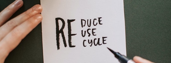 A sticky note with Reduce, Reuse, Recycle written on it in pen
